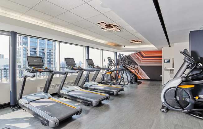 a gym with cardio equipment and a wall of windows