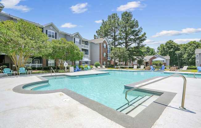 A large swimming pool surrounded by trees and chairs.