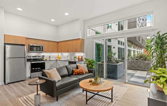 A modern kitchen with a black couch and wooden table.