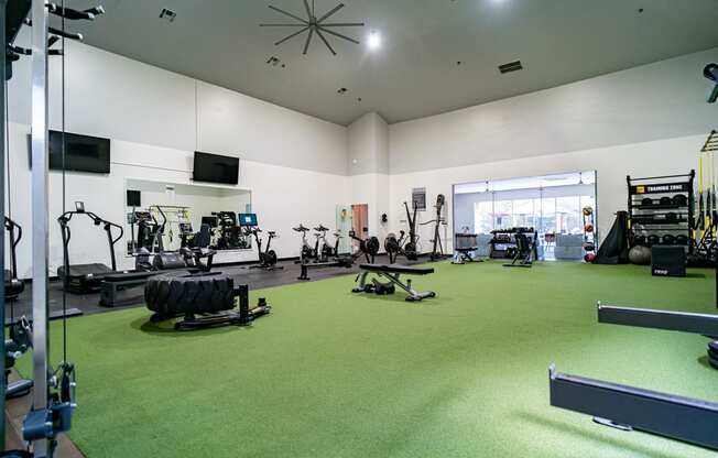 a large fitness room with green carpet and exercise equipment