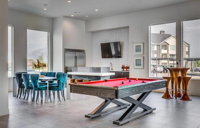 a pool table in a living room with a kitchen  at Affinity 56 Apartments in West Jordan, Utah