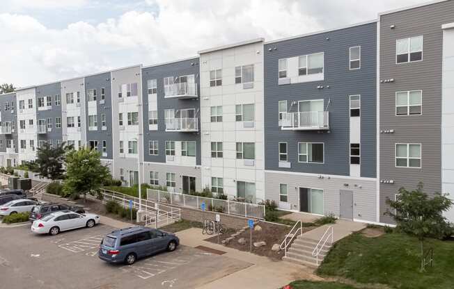 an image of an apartment building with cars parked in a parking lot