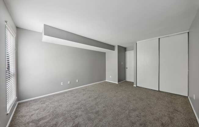 an empty room with carpet and mirrored closet doors