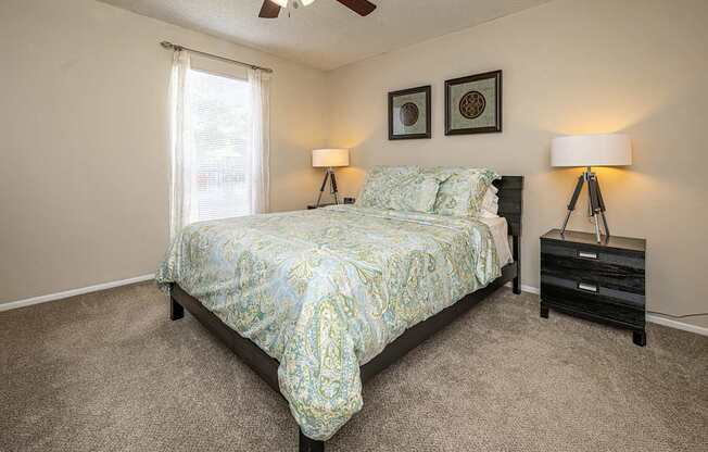 A bedroom with a bed, nightstands, and a ceiling fan.