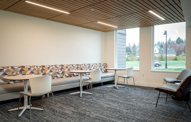 a lounge area with tables and chairs and a large window