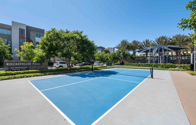 Pet-Friendly Apartments in Irvine, CA - Astoria at Central Park West - Outdoor Pickleball Court with Surrounding Trees.