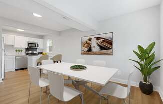 a dining room with a white table and chairs and a white kitchen with stainless steel appliances Kenilworth at Perring Park Apartments, Baltimore, MD 21234