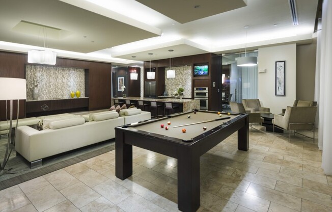 Lounge space with a pool table, seating area with a white leather couch, and catering kitchen