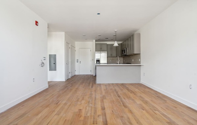 a renovated living room and kitchen with white walls and wood floors