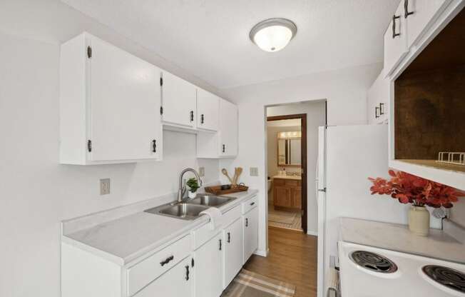 a kitchen with white cabinets and a sink and a white refrigerator