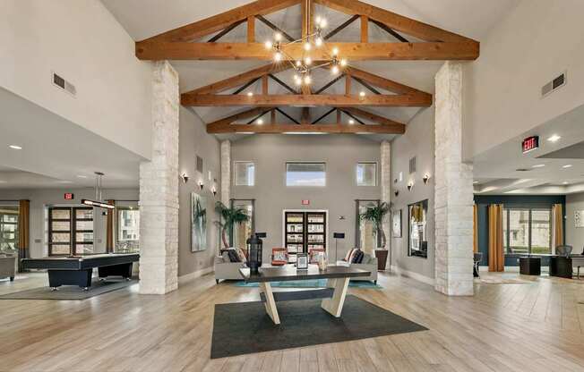 A large room with a wooden beam ceiling and a long table in the middle.