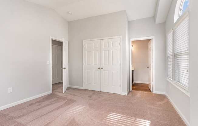 an empty living room with two doors and a door to a hallway
