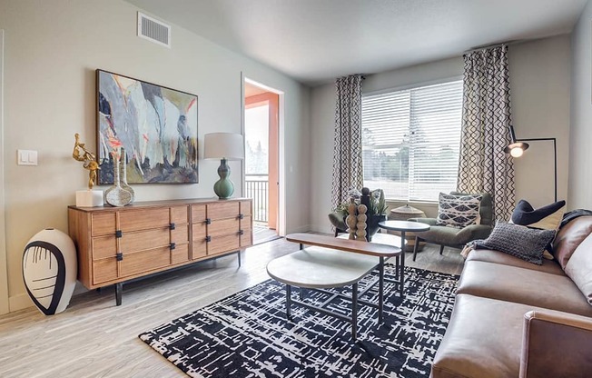 A living room with a brown leather couch, a wooden cabinet, and a large abstract painting on the wall.
