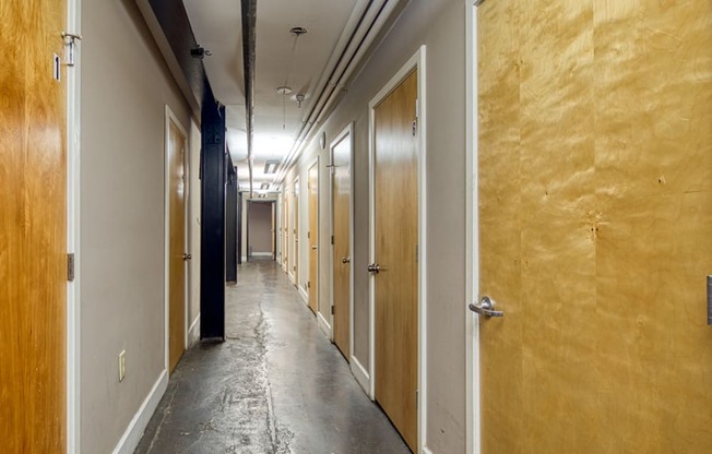 a long hallway with wooden doors and a concrete floor