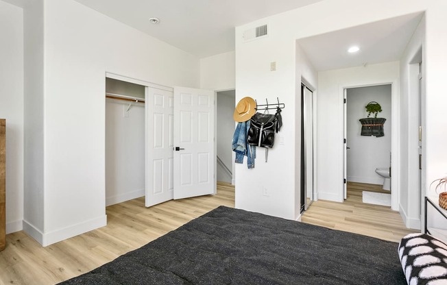 a bedroom with white walls and white closets and a gray rug