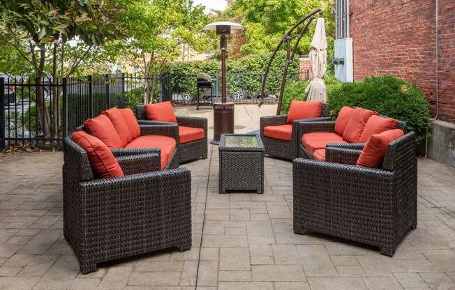 a patio with wicker furniture and orange pillows on it