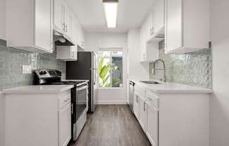 A modern kitchen with white cabinets and a black refrigerator.