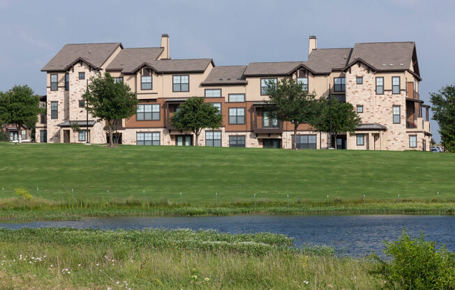 A large house with a brown roof and a green lawn in front.