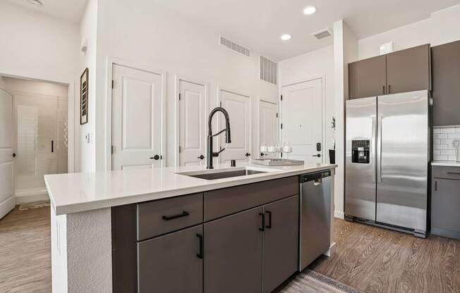 A modern kitchen with a white countertop and dark brown cabinets.