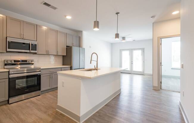 an open kitchen and living room with an island and stainless steel appliances