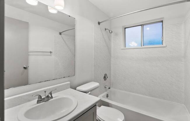 A white bathroom with a window.