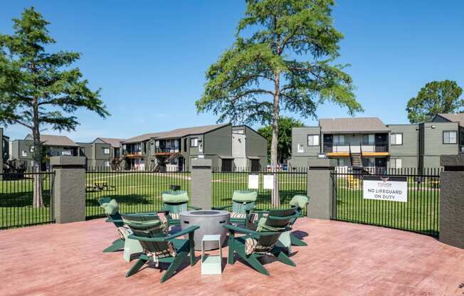 Outdoor seating at Fusion Fort Worth apartments in Haltom City, TX with green Adirondack chairs around a gas fire pit