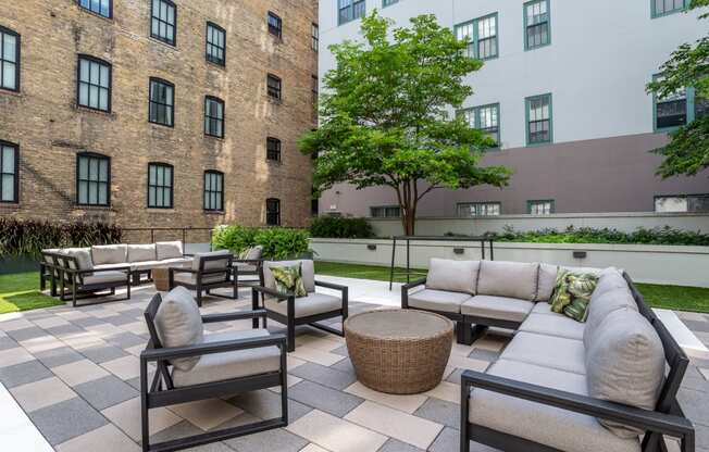 an outdoor patio area with couches and tables and a brick building