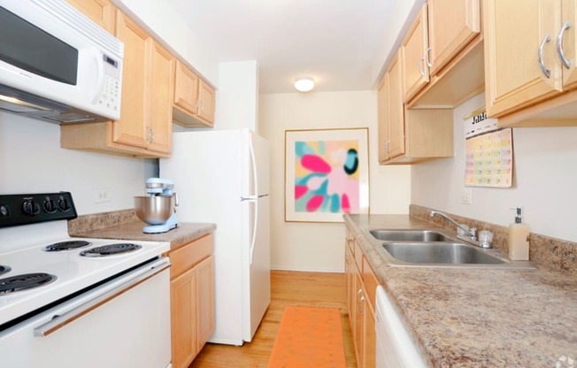 a kitchen with white appliances and granite counter tops and wooden cabinets