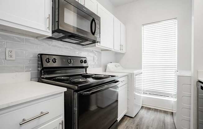 an all white kitchen with black appliances and white cabinets