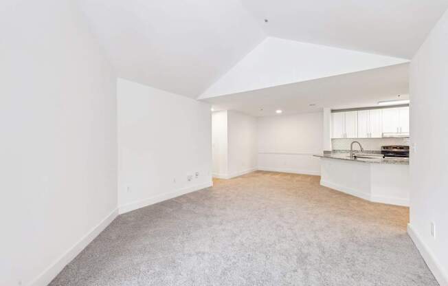 A spacious living room with a carpeted floor and white walls.