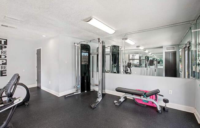A gym with a pink bench and a mirrored wall.