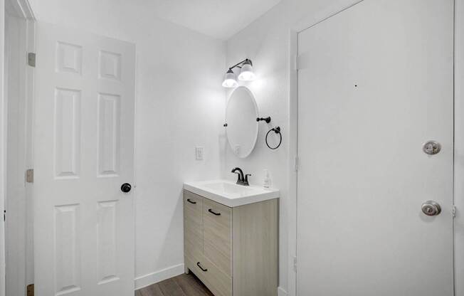 A white bathroom with a sink and a mirror.