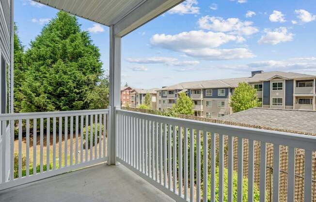 A balcony with a white railing overlooks The Madison Apartments in Olympia, WA
