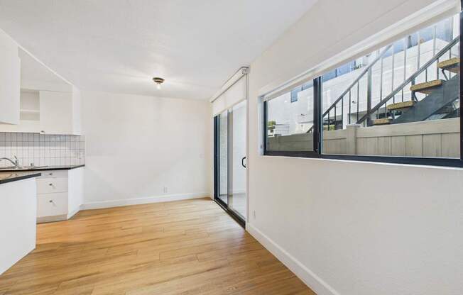 A room with a wooden floor and a staircase outside.
