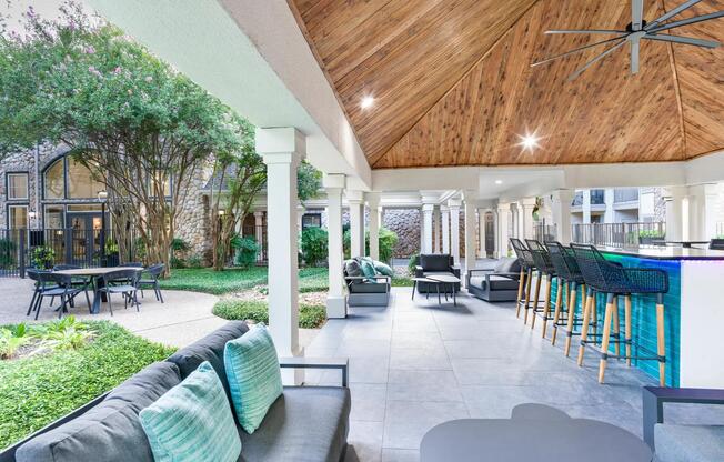Lounge under the pavilion with comfortable seating, a ceiling fan, and a vibrant poolside bar just steps away.