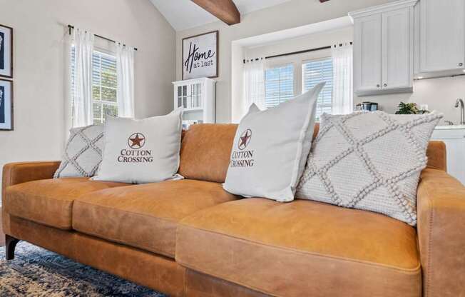 A brown couch with two pillows that say "Cotton Crossing" on it.