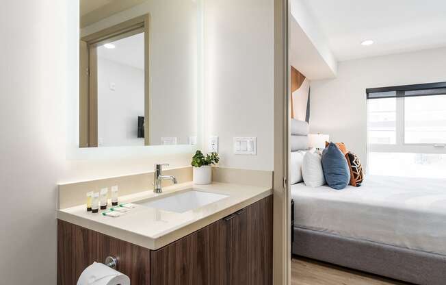 a bathroom with a sink and a mirror next to a bed