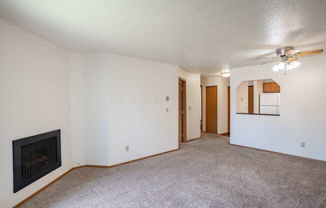 an empty living room with a fireplace and a ceiling fan. Fargo, ND Westview Towers Apartments