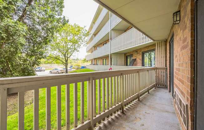 A balcony with a wooden railing and a brick wall on the side.