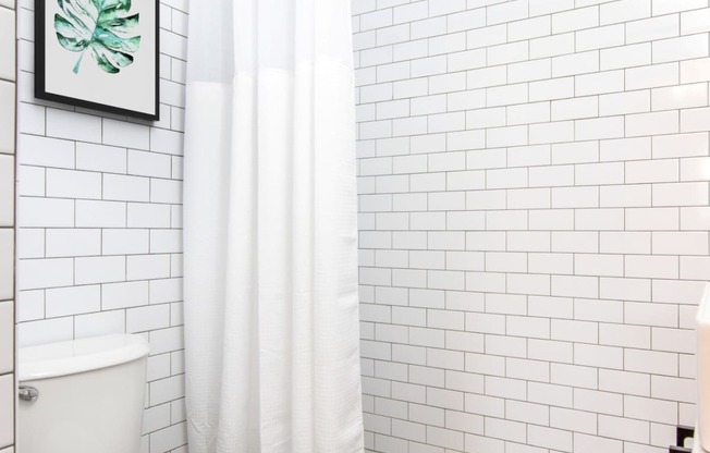 a bathroom with white subway tile and a white shower curtain