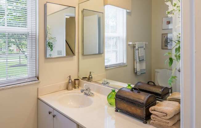 a bathroom with a sink and two mirrors and towels