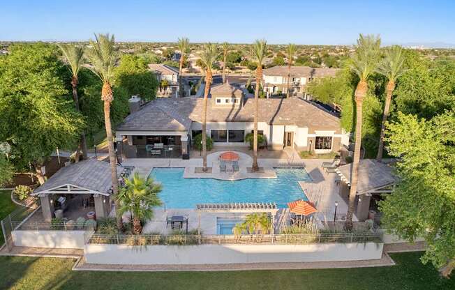 A large house with a pool surrounded by palm trees.