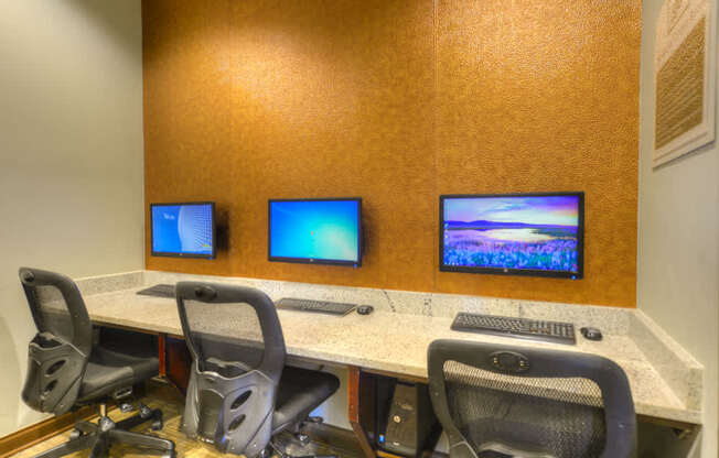 A conference room with a table, chairs, and three monitors.