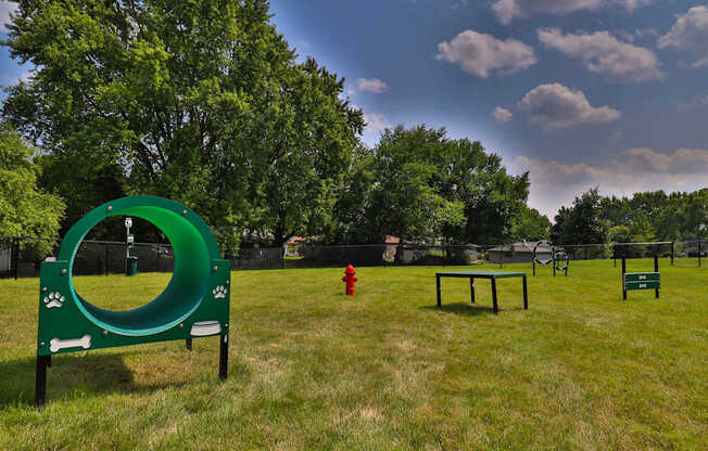 A dog park with a green tunnel and a red fire hydrant.