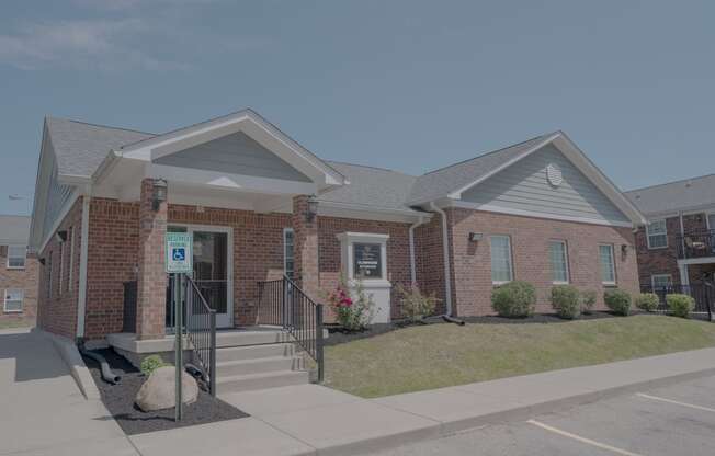 the front of a brick house with a porch and stairs
