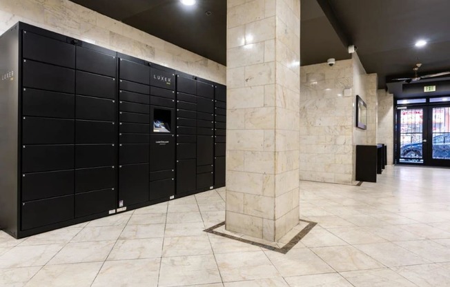 a row of black lockers in a building with a marble pillar