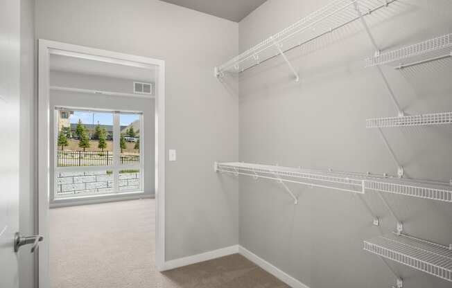 a spacious closet with shelves and hanging racks in a white room with a window
