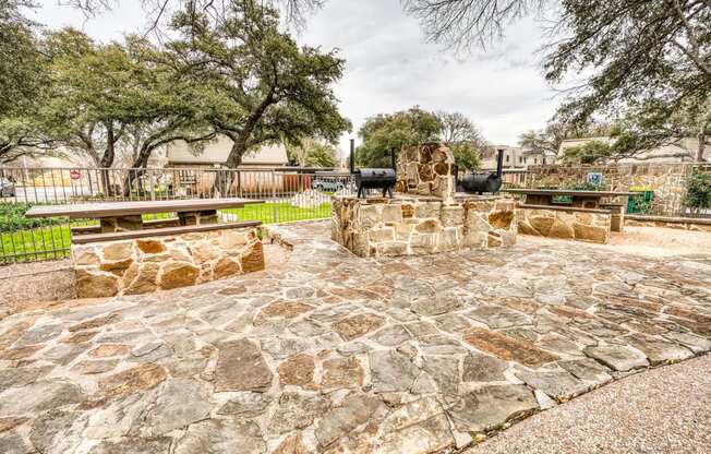 a stone patio with a stone fireplace and benches