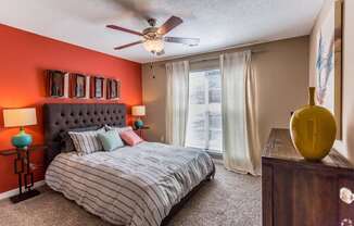 A bedroom with a bed, a dresser, and a ceiling fan.