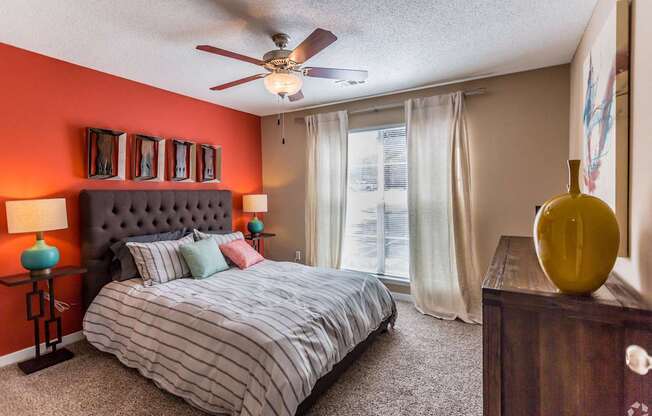 A bedroom with a bed, a dresser, and a ceiling fan.